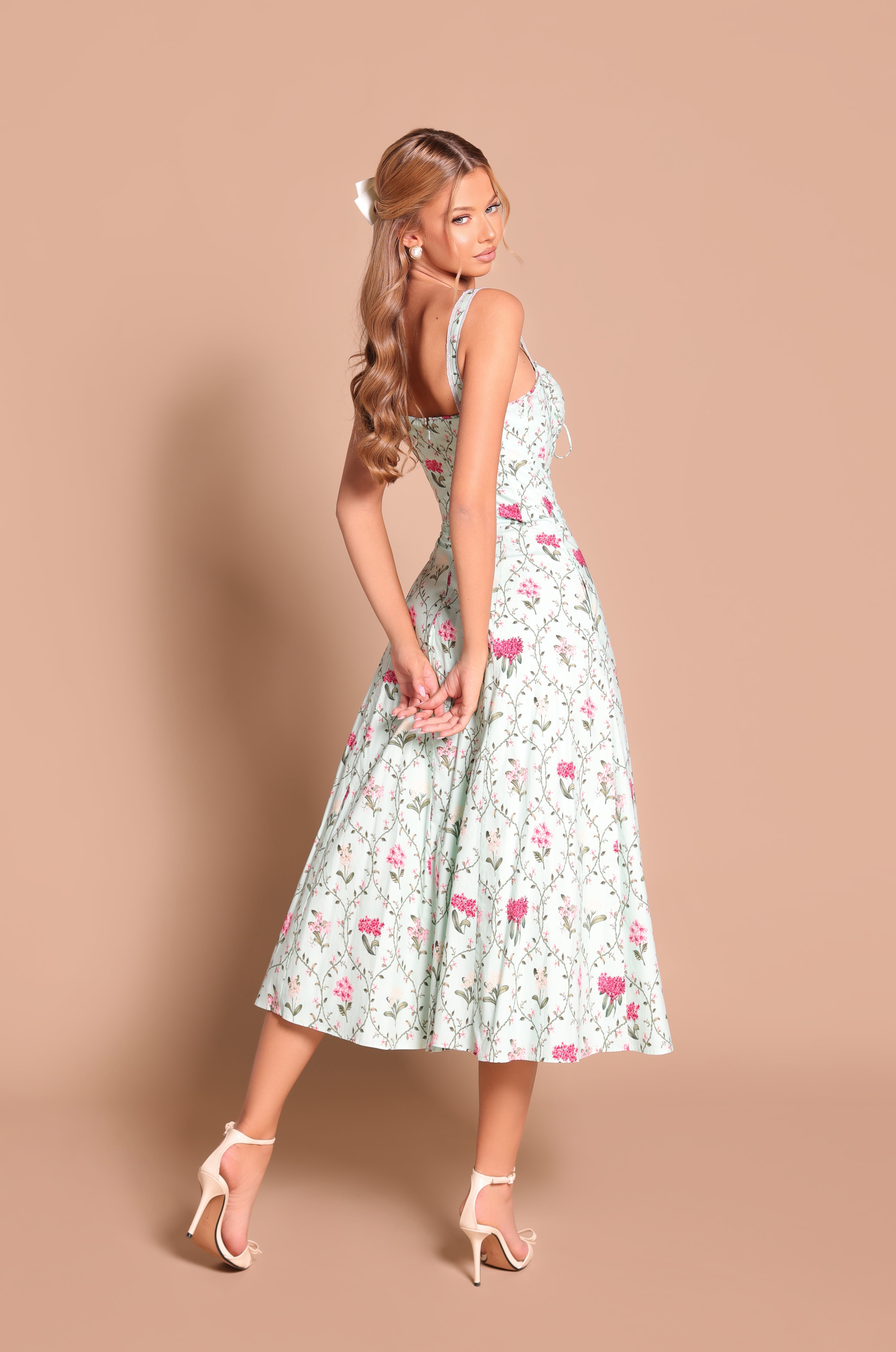 Woman wearing the Mint Green Floral Casual Midi Dress: Celenia and white high-heeled sandals, standing against a beige background, facing backward and looking over her shoulder—ideal for summer weddings.